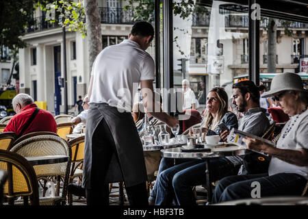 Cameriere che serve i clienti al tradizionale outdoor Cafe' Parigino in centro città. Foto Stock