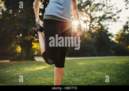 Ritagliato colpo di donna fitness stretching gambe. Modello femminile di esercitare nella mattina presso il parco della città. Foto Stock