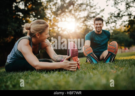 Coppia Fitness stretching all'aperto nel parco. Giovane uomo e donna che esercitano insieme nella mattina. Foto Stock