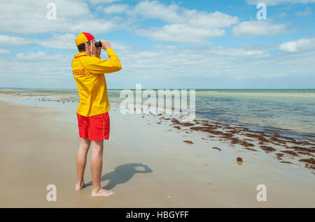 Giovane uomo life saver guardando la situazione sul mare Foto Stock