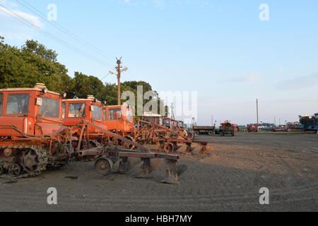 Trattore, in piedi in una fila. Macchine agricole. Foto Stock