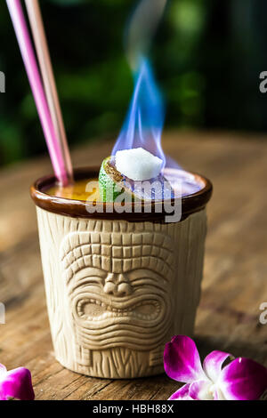 Tiki cocktail per due in un Tiki mug con una fiamma di calce come guarnire e due cannucce Foto Stock