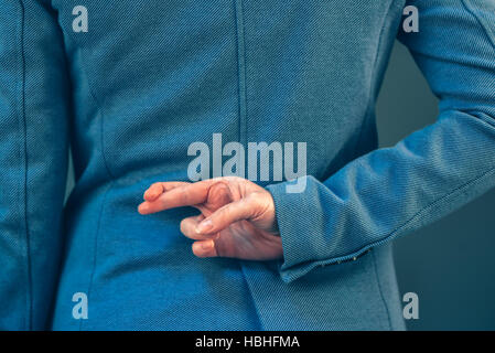 Business donna in elegante tuta blu ha incrociato le dita dietro la schiena come una forma di mano gesto quando le persone sono raccontare bugie Foto Stock