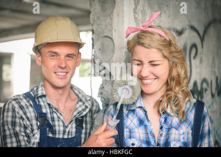 Ritratto di un giovane uomo e donna in tuta con rullo per pittura in mani. Concetto di costruzione e di riparazione della casa. Foto Stock