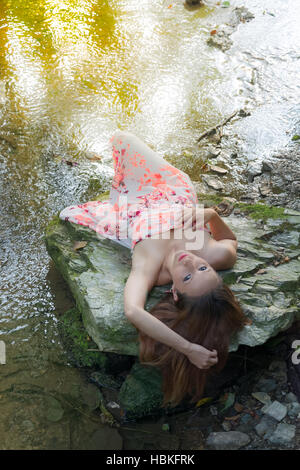 Stupendo giovane donna sdraiata su una roccia Foto Stock