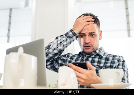 Preoccupato shoked uomo alla ricerca di un portatile presso il cafe Foto Stock