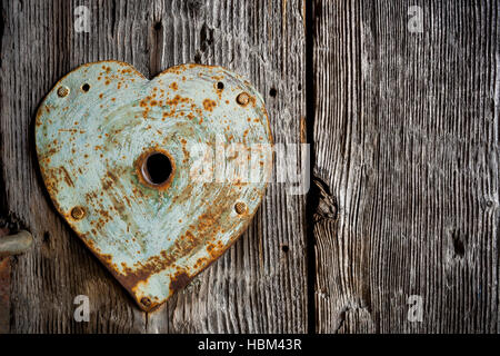 Rusty vecchia modanatura sulla toppa di chiave a forma di cuore sulla vecchia porta di legno. Foto Stock