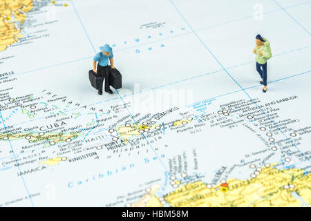 Primo piano della statuetta in miniatura di giovani viaggiatori in piedi sulla grande mappa accanto a isole dei Caraibi Foto Stock