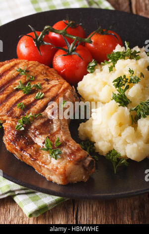Braciole di maiale alla griglia con purè di patate su una piastra di close-up verticale. Foto Stock