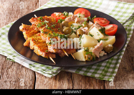 Kebab spagnolo Pinchos Morunos e insalata Patatas Alinadas close-up su una piastra. Posizione orizzontale Foto Stock