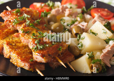 Spagnolo spiedini di carne di maiale - Pinchos Morunos e facile patate con Dressing - Patatas Alinadas closeup su una piastra orizzontale. Foto Stock