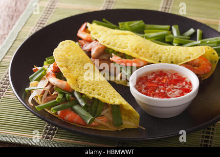 Il vietnamita Banh Xeo Crepes ripiene di carne di maiale, i gamberetti e i germogli di soia e speziato Nuoc Cham salsa closeup su una piastra orizzontale. Foto Stock