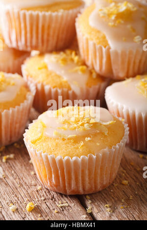 Deliziosi muffin al limone con glassa e zest macro sul piano verticale. Foto Stock