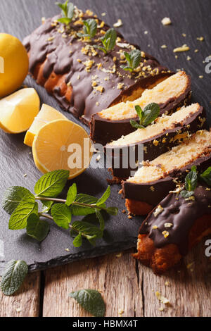 Una deliziosa torta al limone con glassa di cioccolato e scorza di close-up sul piano verticale. Foto Stock