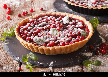 Mirtillo rosso crostata con marmellata, zucchero a velo decorate con la menta vicino sul tavolo orizzontale. Foto Stock