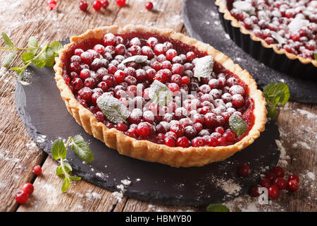 Mirtillo rosso crostata con marmellata, zucchero a velo e menta vicino sul tavolo. Posizione orizzontale Foto Stock