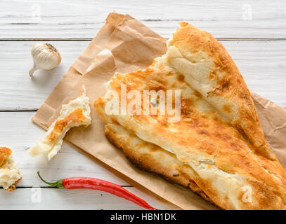 Rotture di metà pane pita caucasici, giacente su di un tagliere. Legno chiaro dello sfondo. Foto Stock