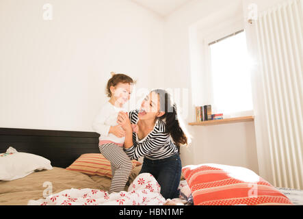 Madre divertendosi con la figlia nella sua camera da letto Foto Stock