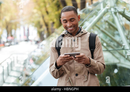 Foto di allegro giovane africano giocare al telefono all'aperto Foto Stock