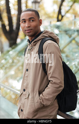 Ritratto di un allegro giovani africani uomo a camminare sulla strada. Guardando a parte. Foto Stock