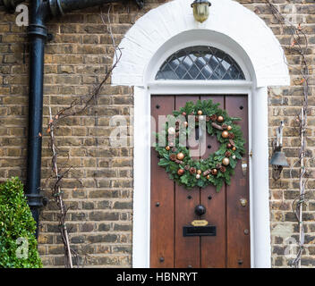 Una festa di Natale corona si blocca sulla porta di una casa nel Royal Borough di Kensington e Chelsea. Londra, Regno Unito. Foto Stock