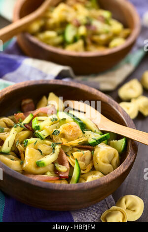 Formaggio cotto al forno tortellini o pulsante di emergenza la pasta con le zucchine, pancetta e timo in ciotole di legno, fotografati con luce naturale (messa a fuoco selettiva Foto Stock