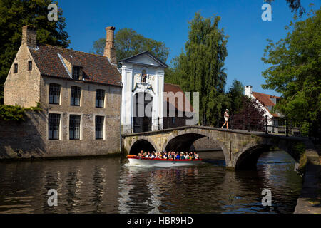 Imbarcazione turistica presso il lago Minnewater e Begijnhof ponte con ingresso al beghinaggio di Bruges, Belgio, Europa Foto Stock