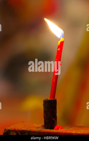 Masterizzazione di rosso, lunghe candele nel tempio budist Foto Stock