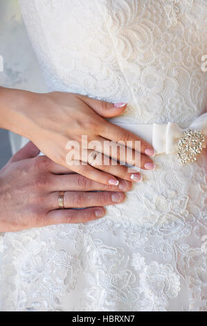 Le mani della sposa e lo sposo con gli anelli sul vestito di sposa Foto Stock