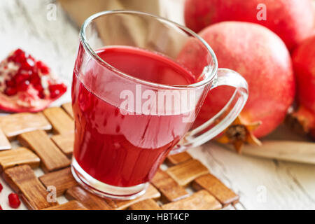 Bicchiere di succo di melograno con frutta fresca su bianco tavola in legno rustico Foto Stock