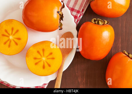 Kaki (Diospyros kaki) servita su piastra bianca. Vista superiore Foto Stock