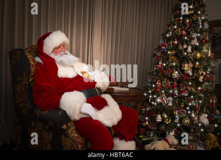 Santa Claus dormire in cattedra in cookie accanto a albero di Natale Foto Stock