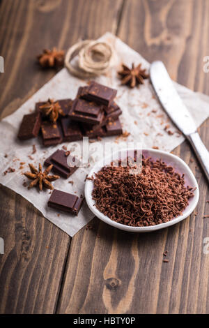 Cioccolato fondente grattugiato con alcuni pezzi di cioccolato sullo sfondo Foto Stock