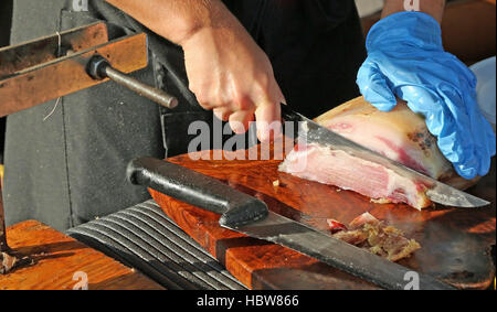 Esperto macellaio affettare la pancetta nel banco dei deli Foto Stock