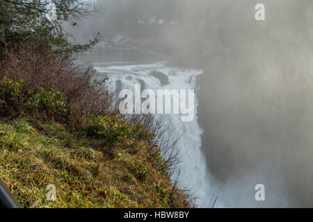 Una nebbia pesante sorge come Snoqualmie Falls giunchi potentemente. Foto Stock