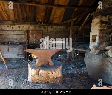 Fabbri strumenti, l'incudine e il martello in un posto centrale nella vecchia officina di fabbro Foto Stock