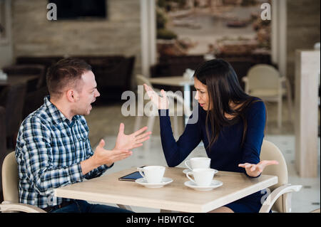 Coppia giovane sostenendo in una caffetteria. Lei ne ha avuto abbastanza, ragazzo è importante scusarsi. Problemi di relazione. Foto Stock