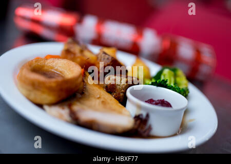 Arrosto con christmas cracker in background per riflettere una cena di natale Foto Stock