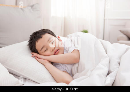 Sei-anno-vecchio ragazzo coreano dormire nel letto Foto Stock