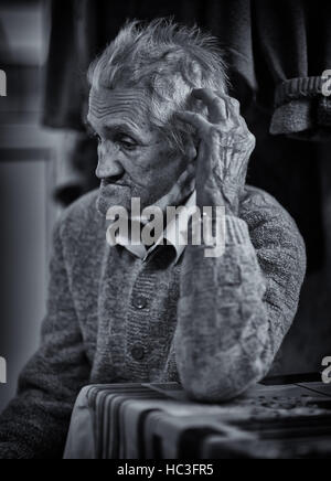 Primo piano di un vecchio uomo indoor, dai toni monocromatici Foto Stock