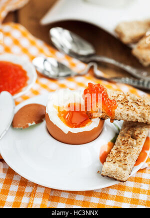 Uova sode con caviale rosso, pane tostato e caffè per colazione Foto Stock