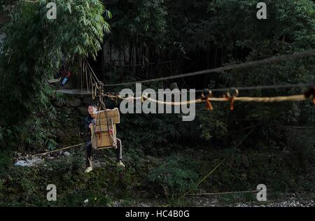 (161208) -- CHONGQING, 8 dicembre, 2016 (Xinhua) -- Li Gaoqiang porta 'Tuhuo' carta per vendere su altra banca tramite una slitta in città Xinglong, a sud-ovest della Cina di Chongqing, 7 dicembre, 2016. Li la famiglia, vivendo in Xinglong città di Chongqing ha tramandato l'artigianato tradizionale di rendere "Tuhuo' carta attraverso cinque generazioni. "Tuhuo' carta, fatto di bambù che cresce in aree locali, richiede elevati standard di tecniche attraverso tutte le fasi di lavorazione. Tuttavia, ad alta intensità di manodopera, scarse vendite e bassi rendimenti, l'imbarcazione viene ereditato da alcuni giovani, che ha spinto il governo a de Foto Stock