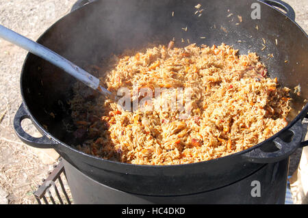 La cottura pilaf piatto in outdoor. pilaf in un calderone, cibo di strada Foto Stock