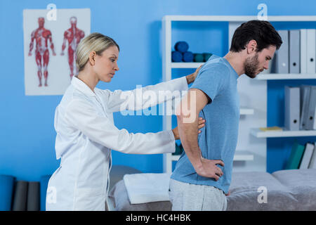 Fisioterapista esaminando le mans indietro Foto Stock