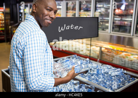 Uomo che guarda un bottiglia di acqua nel supermercato Foto Stock