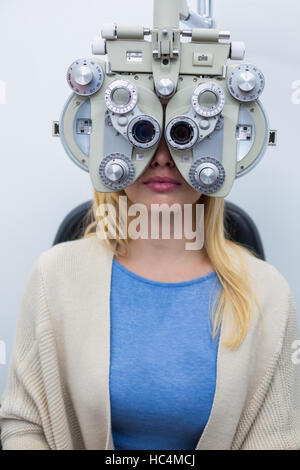 Paziente femmina cerca attraverso phoropter durante la visita oculistica Foto Stock