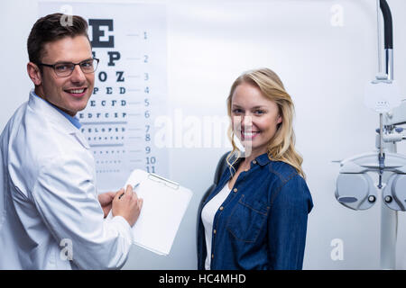 All'ottico optometrista discutendo occhio report di test con paziente femmina Foto Stock