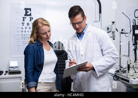 All'ottico optometrista discutendo occhio report di test con paziente femmina Foto Stock