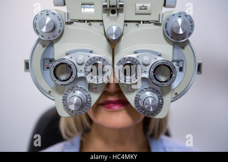 Paziente femmina cerca attraverso phoropter durante la visita oculistica Foto Stock