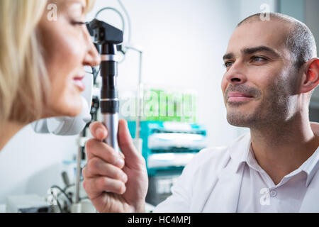 All'ottico optometrista esame paziente femmina attraverso oftalmoscopio Foto Stock